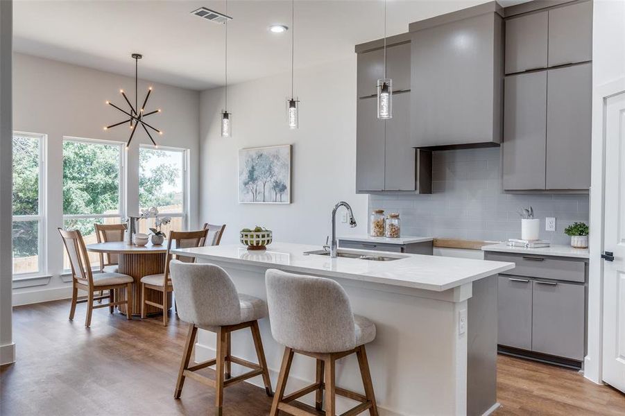 Kitchen with gray cabinets, light wood-type flooring, and backsplash