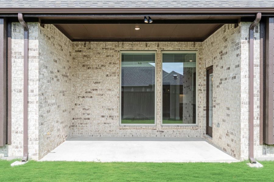 Covered back patio with concrete floor, brick exterior walls, large sliding glass door, and recessed lighting overhead.