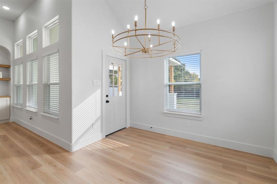 Foyer entrance with light wood-type flooring and a chandelier