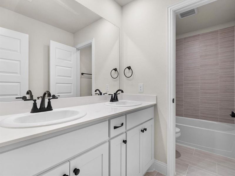 Bathroom with double vanity and bathtub / shower combination