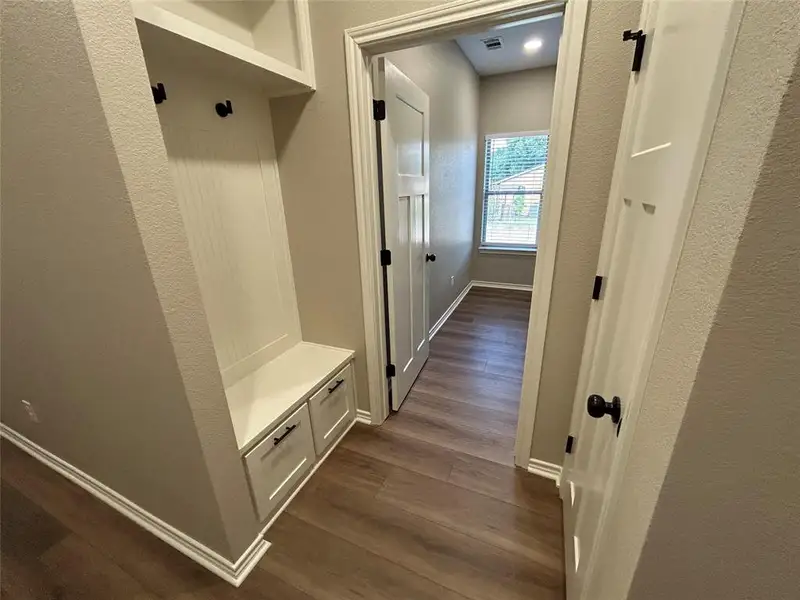 Mudroom with a textured wall and dark wood-type flooring