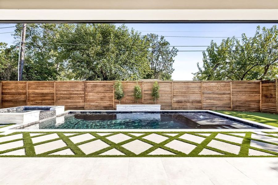 Fenced backyard with a patio and a pool with connected hot tub Fenced backyard with a patio and a pool with connected hot tub