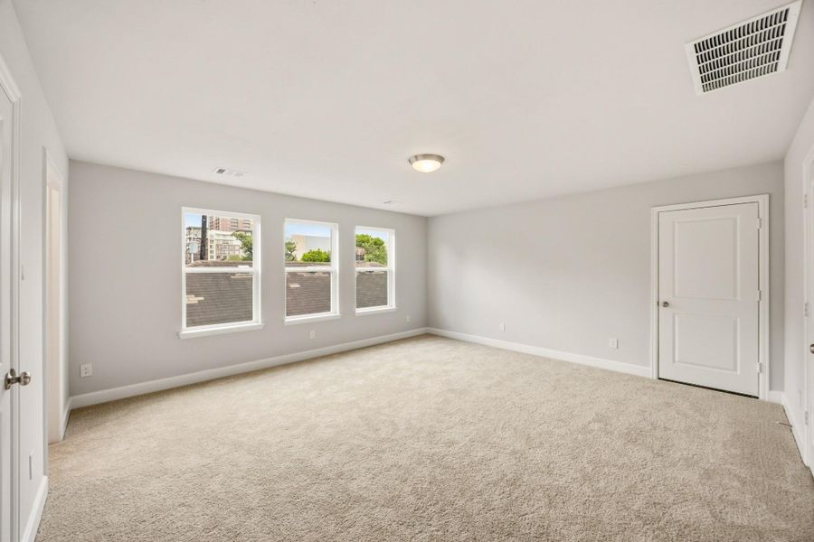 A remarkably large third-floor bedroom basks in brightness, featuring an ensuite bathroom and access to a substantial walk-in storage closet, ensuring privacy and comfort. A remarkably large third-floor bedroom basks in brightness, featuring an ensuite bathroom and access to a substantial walk-in storage closet, ensuring privacy and comfort.