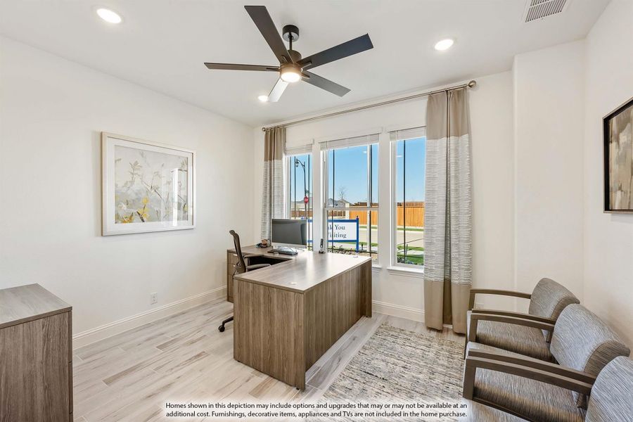 Home office with wood desk, ceiling fan, light hardwood floors, and large windows with neutral drapes Home office with wood desk, ceiling fan, light hardwood floors, and large windows with neutral drapes