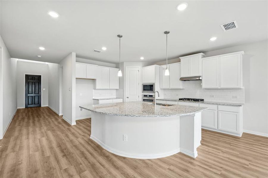Kitchen with light wood-type flooring, tasteful backsplash, white cabinets, and recessed lighting Kitchen with light wood-type flooring, tasteful backsplash, white cabinets, and recessed lighting