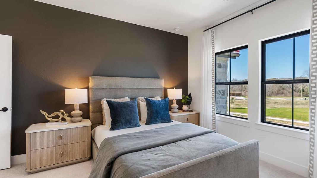 A secondary bedroom with two large windows, neutral painted walls, and wood flooring.