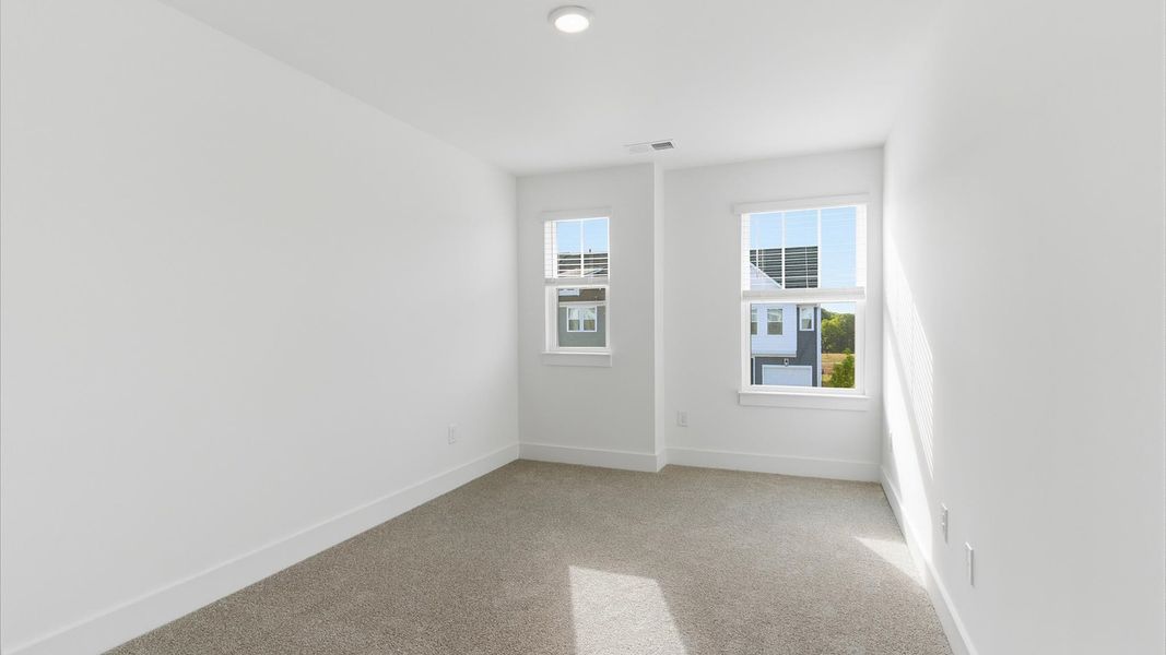 Bright and serene bedroom with comfortable carpeted flooring and large windows for vibrant light