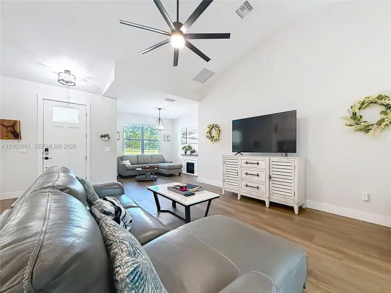 Vaulted ceilings, wood-finish flooring, multi-blade ceiling fan, and recessed lighting