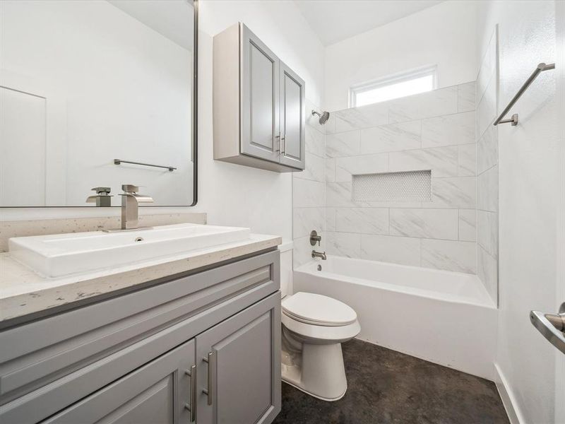 Full bathroom with toilet, tiled shower / bath combo, vanity, and concrete flooring