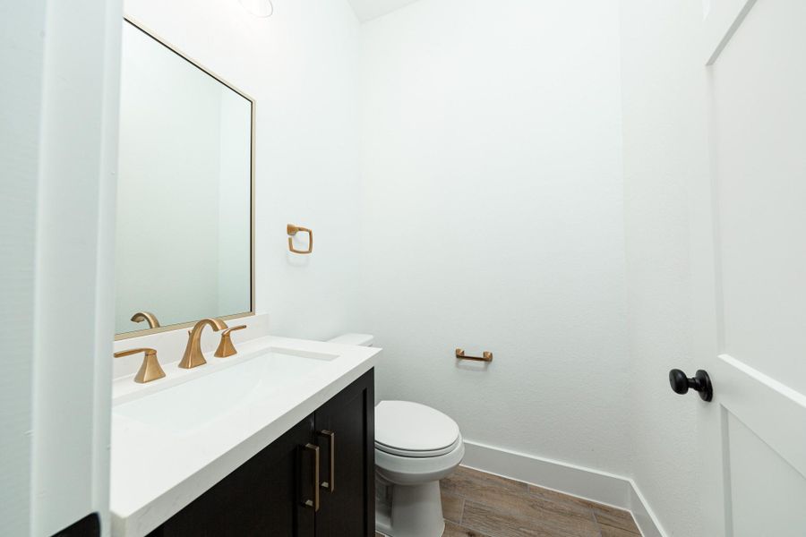 The powder bath features a stylish vanity with framed mirror, and a clean, modern design.