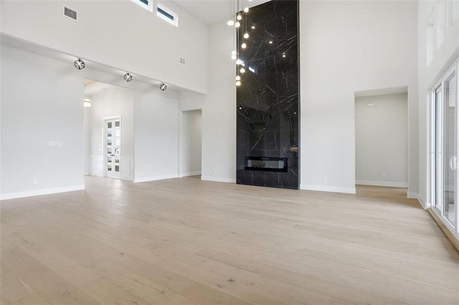 Spacious living room showcasing soaring ceilings, a dramatic floor-to-ceiling fireplace, and an open layout connecting the foyer, private office, and main living areas.