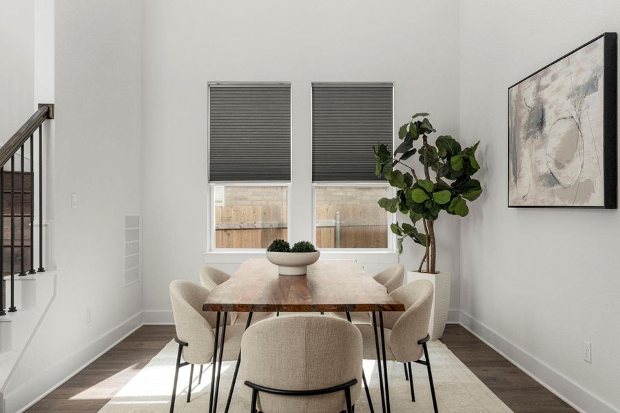 A well-lit dining area featuring dark wood flooring and a classic wooden table, perfect for gatherings.