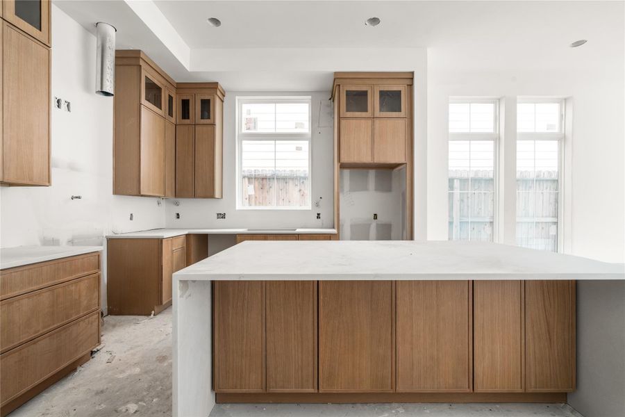 This home's kitchen comes with Taj Mahal counters, oversized island with storage on both sides, white oak slim shaker cabinetry, luxury Bosch appliances, Delta champagne bronze fixtures, and white oak wood flooring.