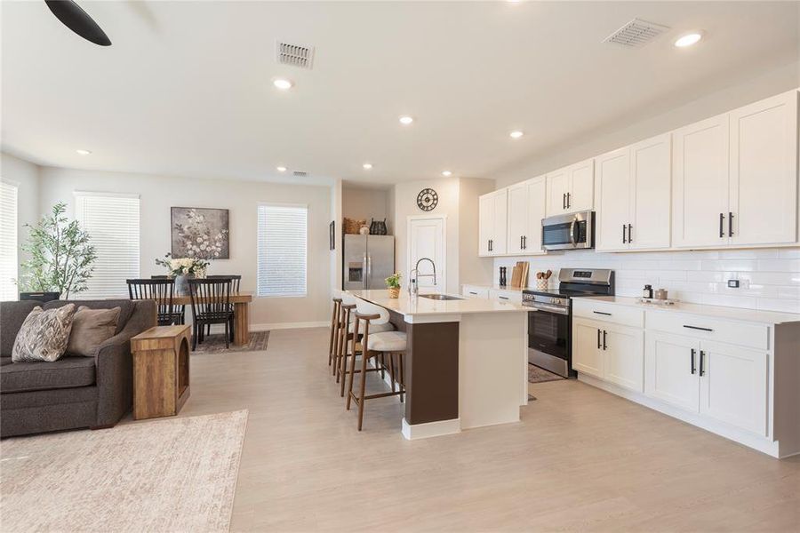 Open-concept living space featuring wood-finish flooring, recessed lighting, and white cabinetry Open-concept living space featuring wood-finish flooring, recessed lighting, and white cabinetry