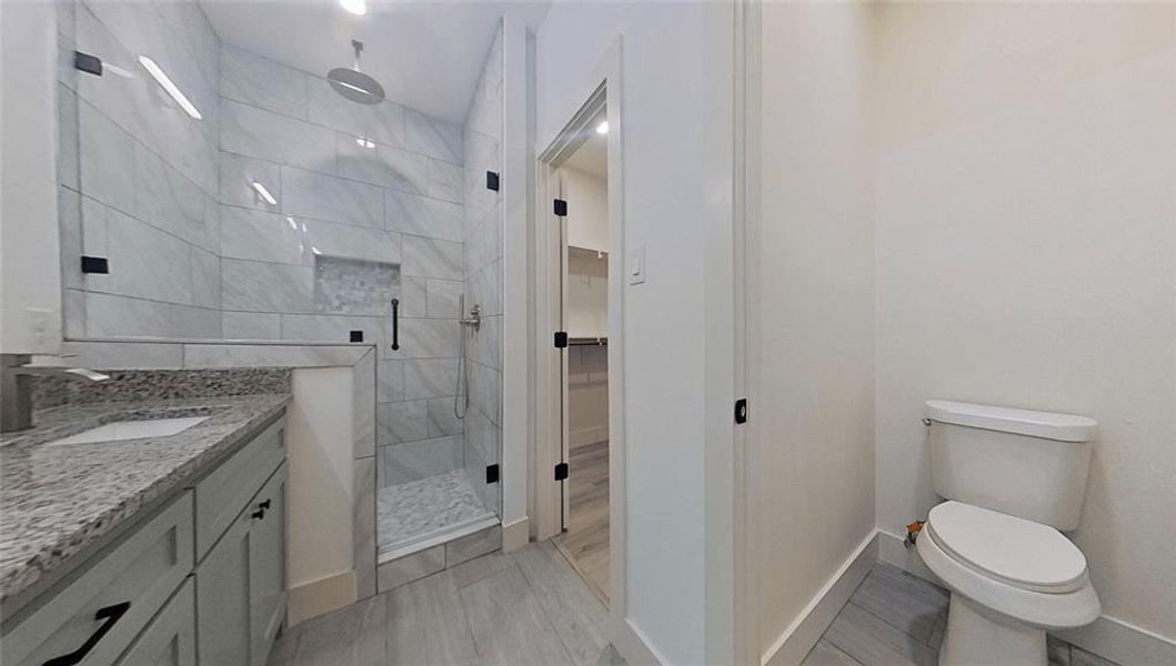 Bathroom featuring vanity, a shower stall, a walk in closet, and light wood finished floors