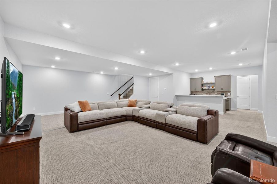 Basement Living Area to Bar View – Generous open floor plan showcasing the large sitting area, stair access, and convenient bar setup for entertaining.