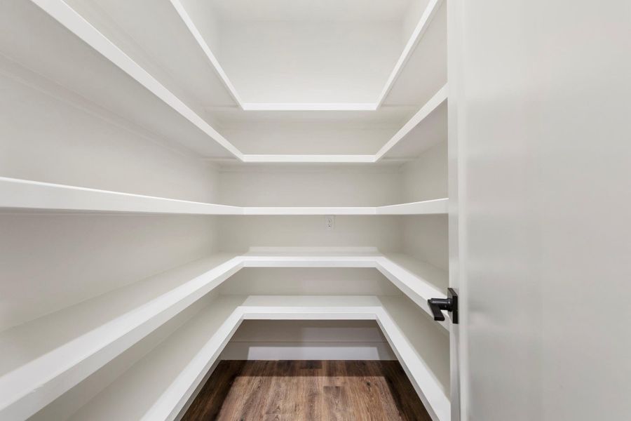 Spacious walk-in pantry with multiple white shelves, perfect for ample storage and organization.