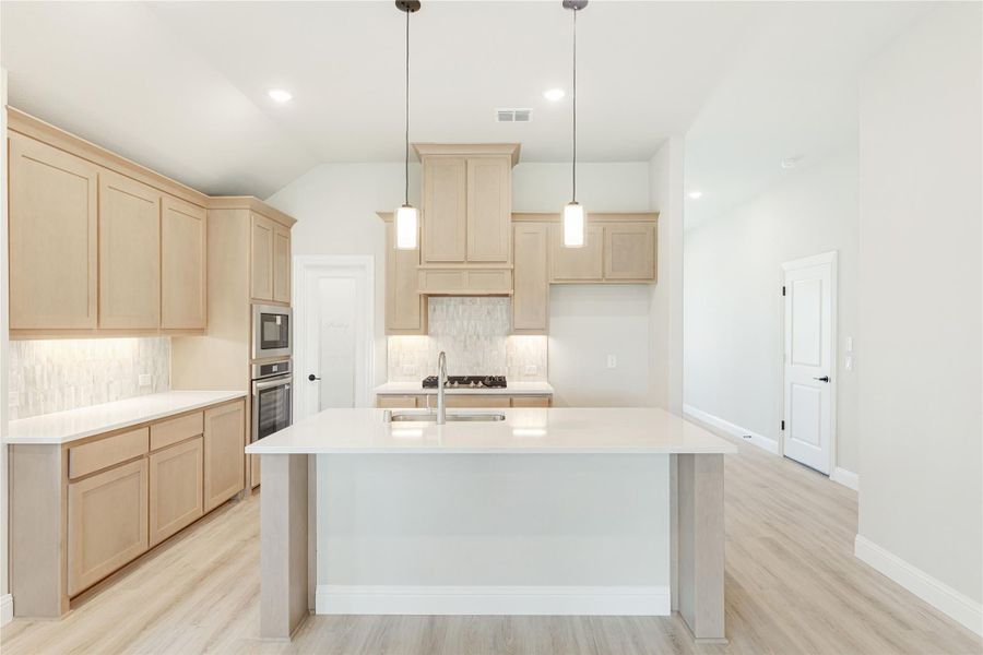 Kitchen with large center island, light wood cabinets, white countertops, and pendant lights over island