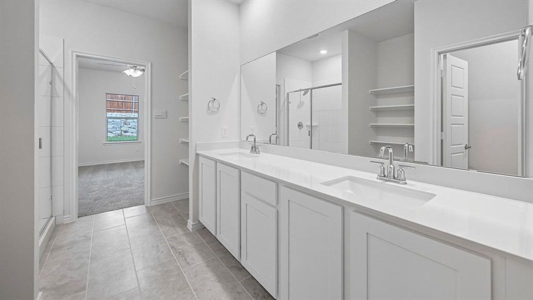 Bathroom featuring a stall shower, double vanity, light tile patterned floors, and a closet Bathroom featuring a stall shower, double vanity, light tile patterned floors, and a closet