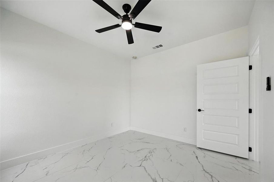 Unfurnished room with ceiling fan and marble finish floors