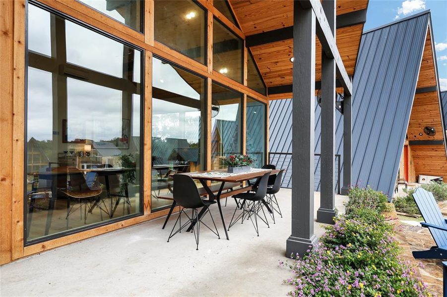 An architectural masterpiece is the floor-to-ceiling wall of windows, providing uninterrupted views of this serene covered patio.  This transparent barrier seamlessly merges indoor comfort with the allure of outdoor living.