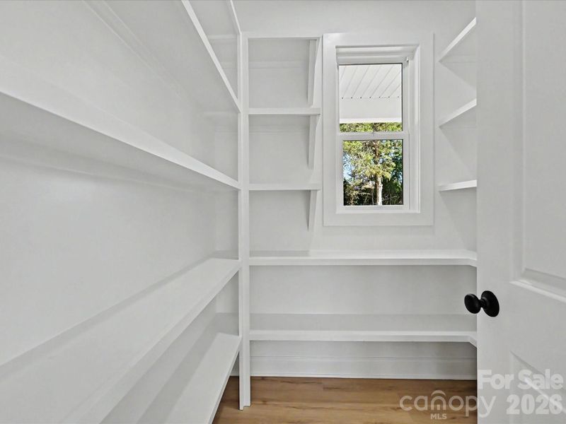 Spacious walk-in pantry with custom built-in shelving and natural light offers exceptional storage and organization for everyday convenience.