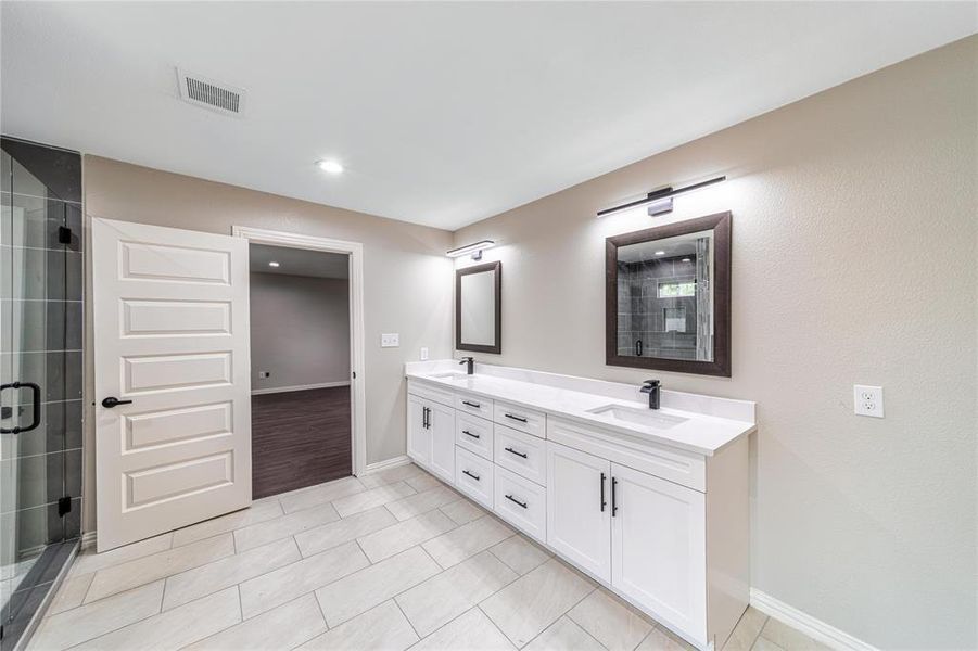 Full bathroom with double vanity, a shower stall, and light tile patterned flooring