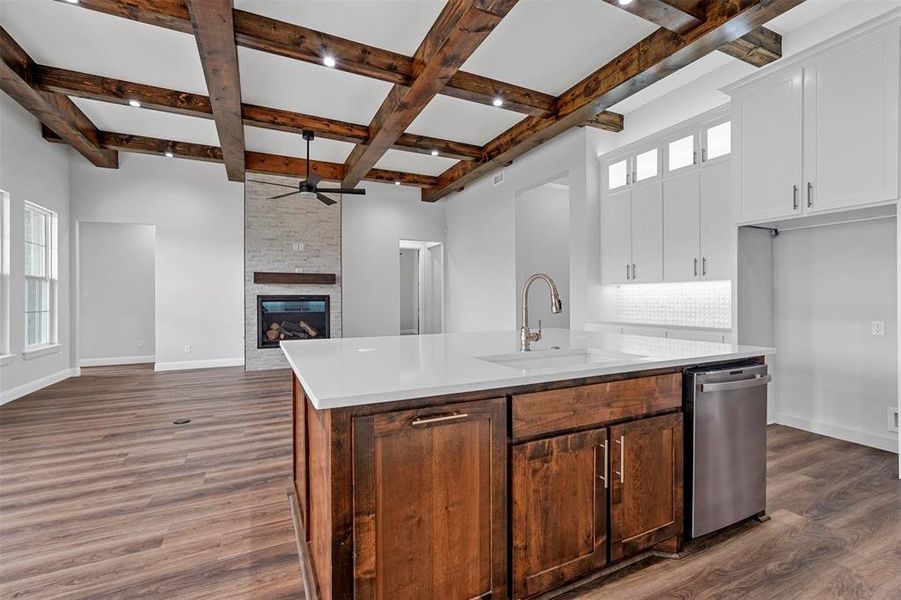 Kitchen with a fireplace, a center island with sink, ceiling fan, sink, and dishwasher