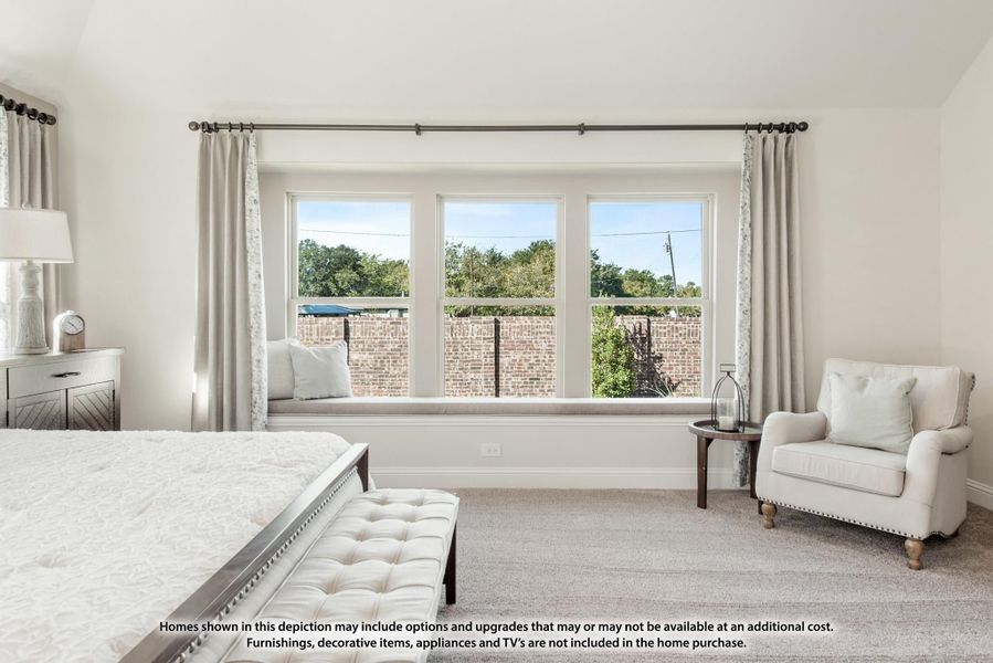 Bedroom with large triple window, built-in window seat, neutral carpet, and sitting area with armchair