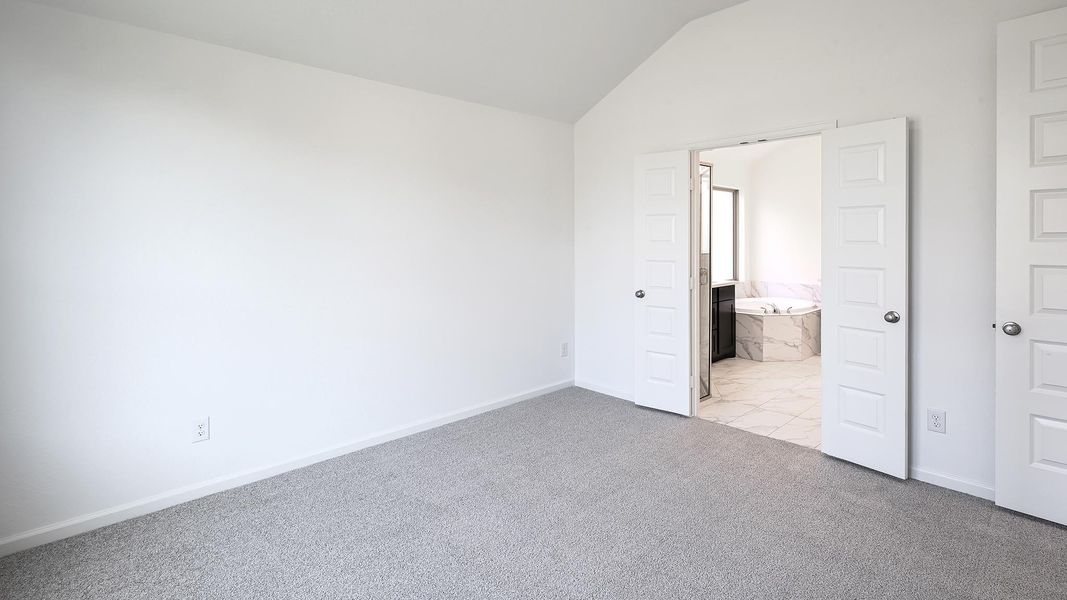 Unfurnished bedroom with vaulted ceiling, light carpet, and ensuite bath Unfurnished bedroom with vaulted ceiling, light carpet, and ensuite bath