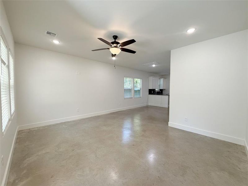 Unfurnished living room featuring finished concrete flooring, ceiling fan, and recessed lighting