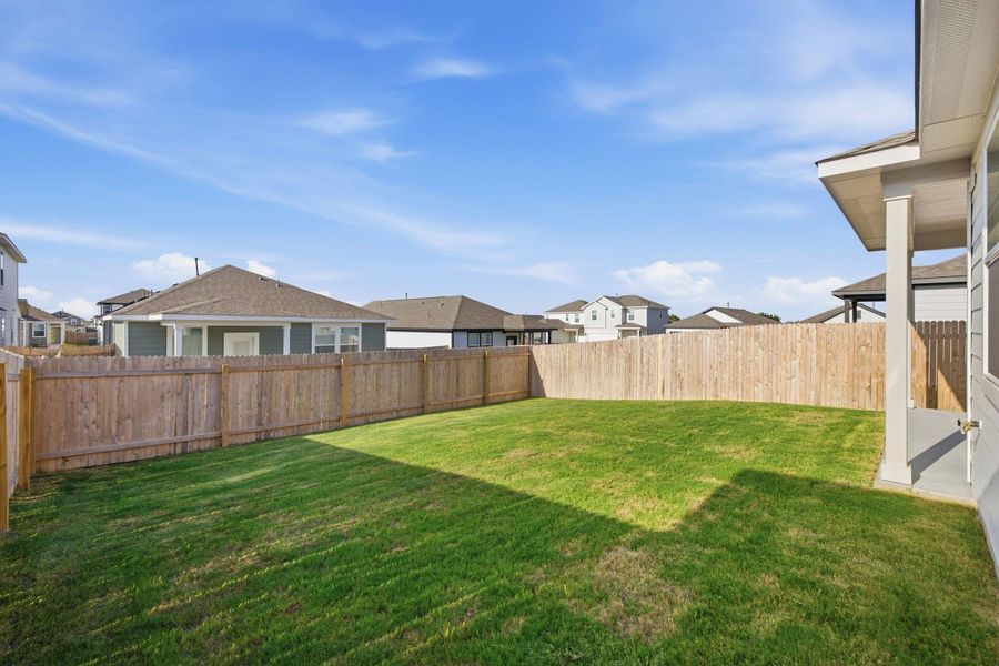 A spacious backyard with fresh green grass is fully enclosed by a privacy fence, perfect for outdoor activities.