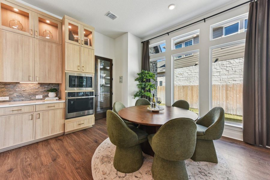 Natural light floods this dining area through towering windows overlooking the fenced yard.