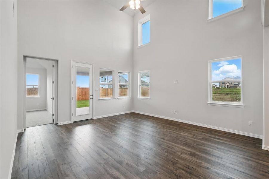 Unfurnished living room featuring a high ceiling, dark wood-type flooring, and ceiling fan
