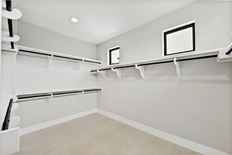 Well-lit walk-in closet with ample storage solutions, featuring high ceilings and natural illumination.