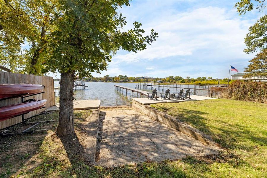 Dock area featuring a boat ramp, a water view, and a lawn