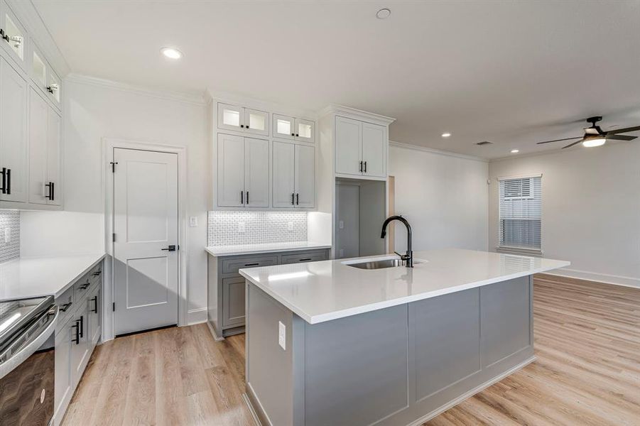 Kitchen with light wood finished floors, crown molding, ceiling fan, and a sink Kitchen with light wood finished floors, crown molding, ceiling fan, and a sink