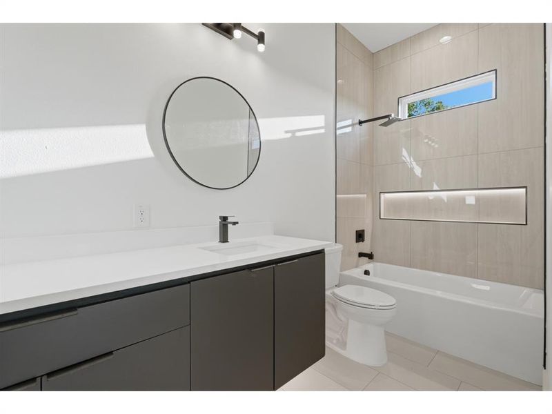 Contemporary bathroom featuring a dark gray floating vanity with a white countertop and a circular mirror