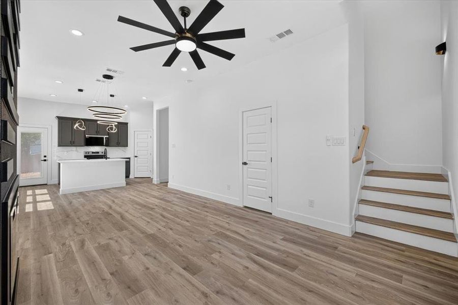Open-concept living area featuring wood-finish flooring, recessed lighting, and a contemporary ceiling fan Open-concept living area featuring wood-finish flooring, recessed lighting, and a contemporary ceiling fan
