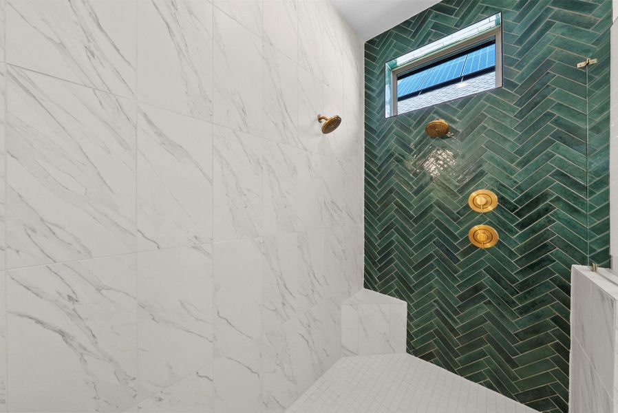 Spa-like walk-in shower featuring marble-look tile, striking green herringbone accent wall, and premium gold fixtures.