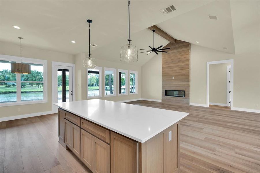 Kitchen with light hardwood / wood-style flooring, a fireplace, a center island, and beam ceiling