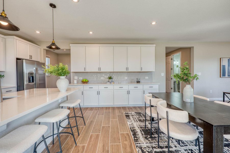 Streamlined cabinetry and wood-look tile floors define this open kitchen and dining area. Streamlined cabinetry and wood-look tile floors define this open kitchen and dining area.