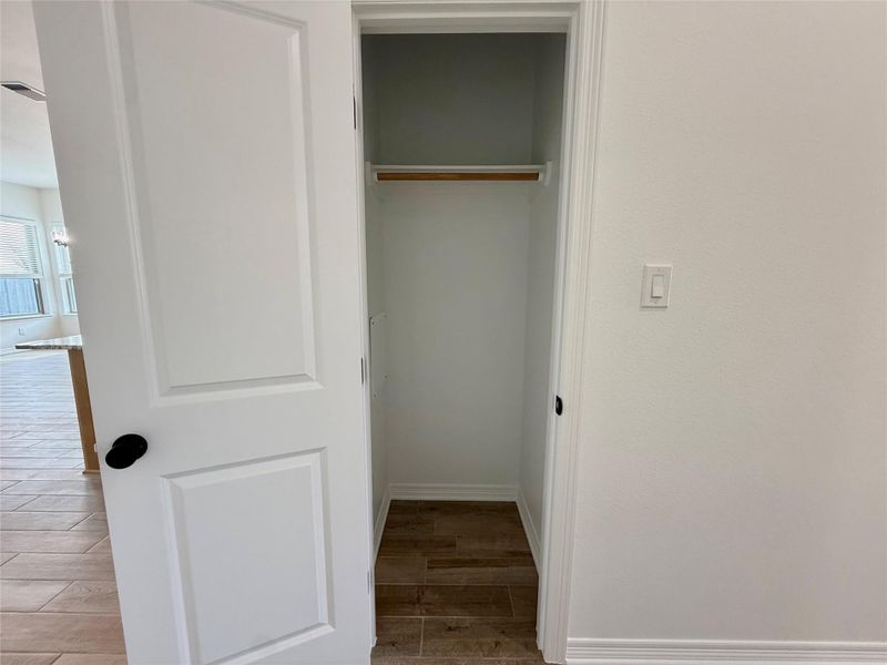 Interior closet with wood-finish flooring, a single wood hanging rod, and white painted walls