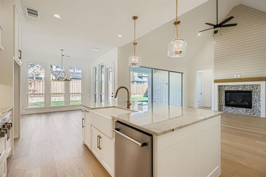 Kitchen featuring white cabinets, pendant lighting, open floor plan, healthy amount of natural light, and high vaulted ceiling Kitchen featuring white cabinets, pendant lighting, open floor plan, healthy amount of natural light, and high vaulted ceiling