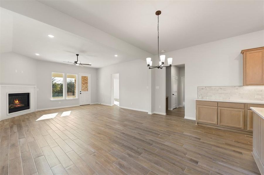 Unfurnished living room with recessed lighting, a glass covered fireplace, a ceiling fan, light wood-style floors, and a chandelier Unfurnished living room with recessed lighting, a glass covered fireplace, a ceiling fan, light wood-style floors, and a chandelier