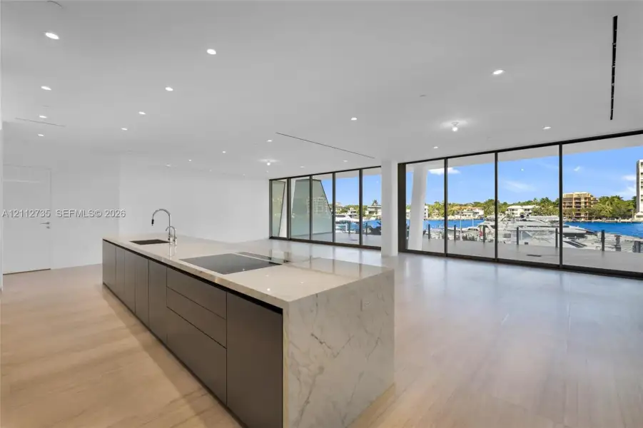 Kitchen island featuring waterfall-edge stone countertop, induction cooktop, and matte-finish cabinetry