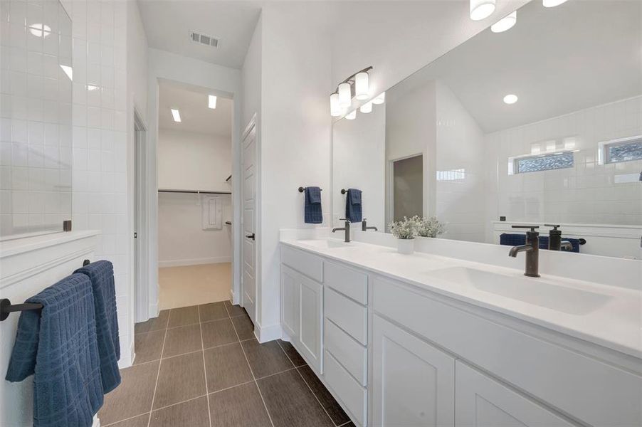 Spacious bathroom featuring a dual vanity with white cabinetry and integrated sinks