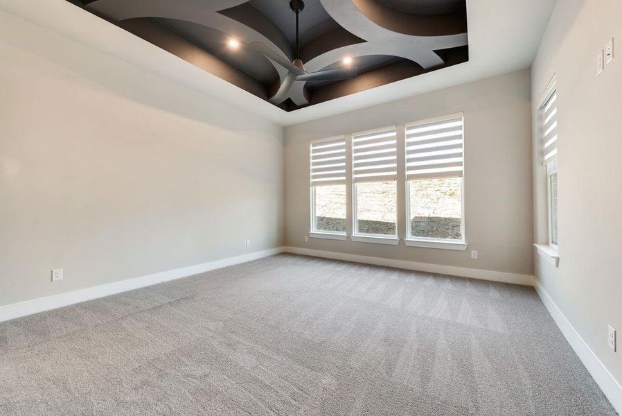 Empty room with light colored carpet and a tray ceiling