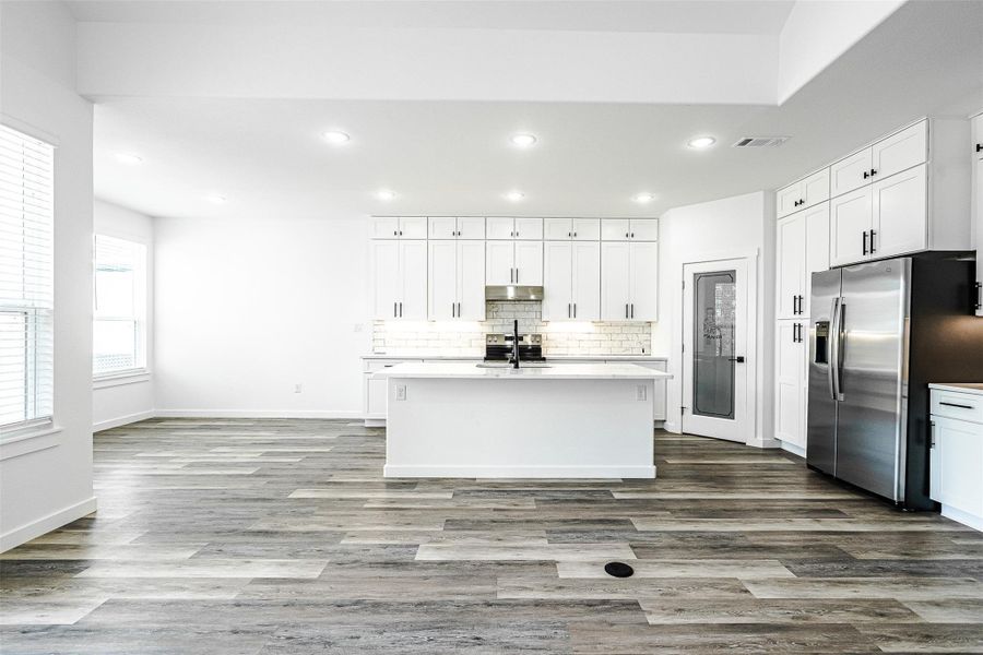A pristine, well-lit kitchen with a central island and contemporary appliances, featuring sleek cabinetry. A pristine, well-lit kitchen with a central island and contemporary appliances, featuring sleek cabinetry.