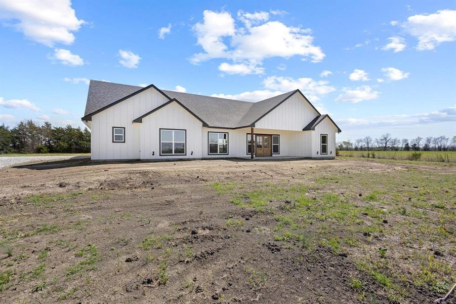 The property features a white exterior with black trim, a dark gray roof, and prominent windows providing ample natural light